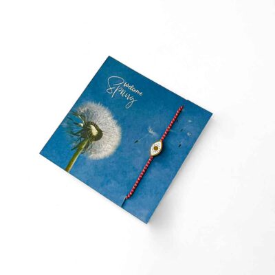 μαρτάκι a blue card with a red cord and a bracelet on it